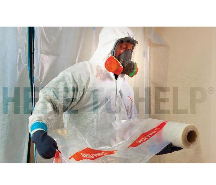 Technician applying plastic sheeting in a mold damaged home