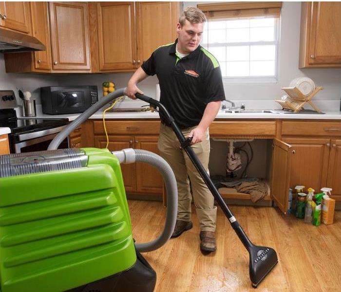 technician removing water damage from a kitchen floor